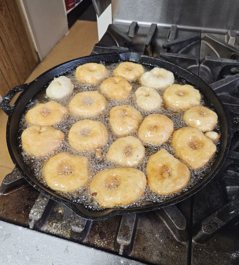 Bannock frying in a cast-iron pan on the stove.