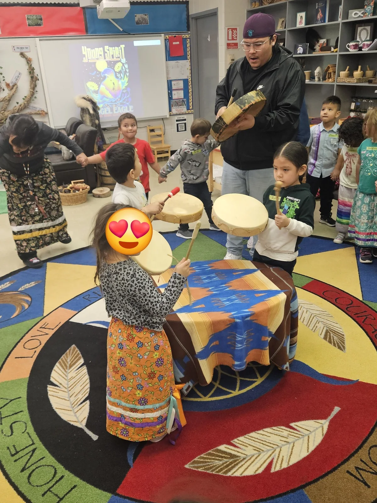 Children and staff watching the dancer from around the rug.